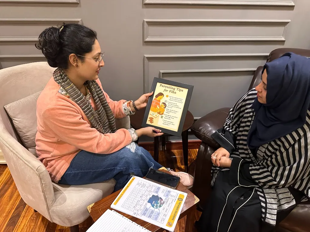 Counselor showing a parenting guide to a mother during a one-to-one session