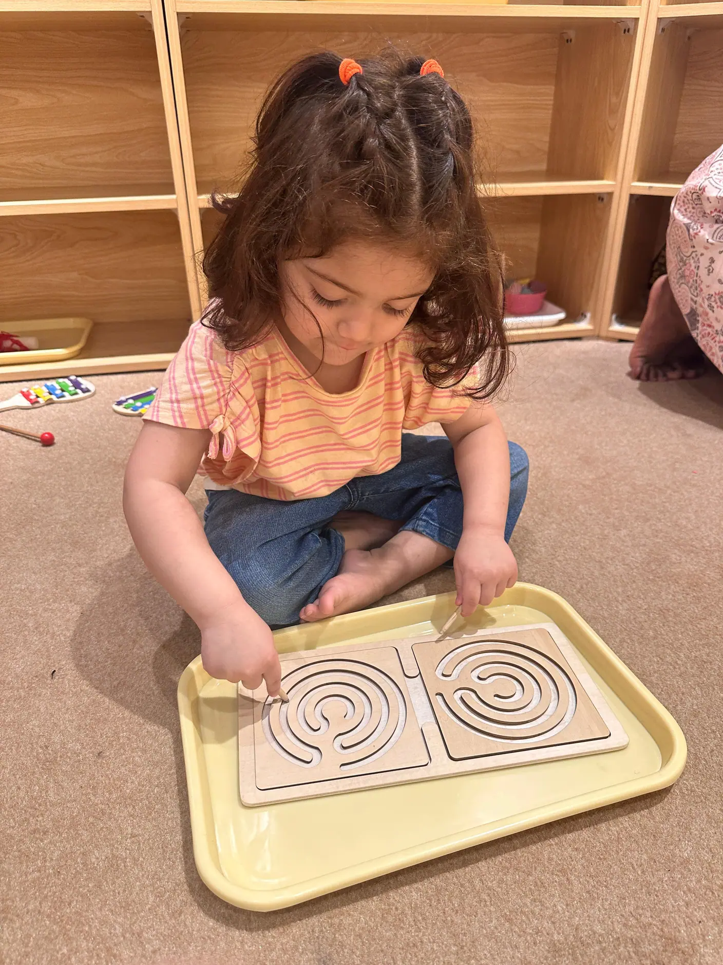Girl tracing a wooden maze board with her finger in a Brain Lab School classroom